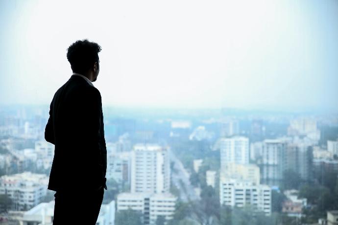 man in black suit standing on top of building looking at city buildings during daytime